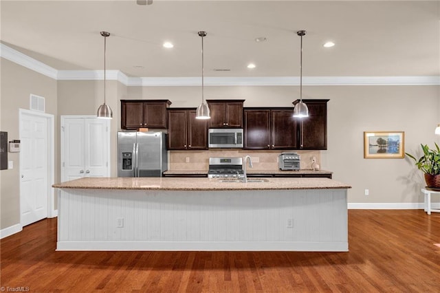 kitchen featuring stainless steel appliances, decorative light fixtures, dark hardwood / wood-style floors, and a kitchen island with sink