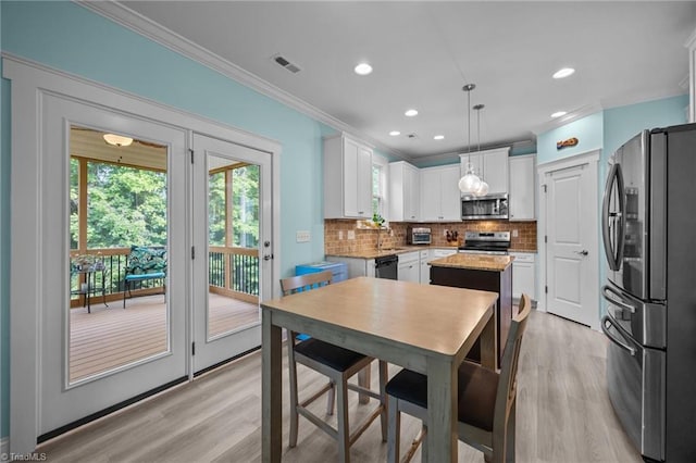 7615 Mary Ellen Ct, Greensboro, NC 27409 - kitchen with stainless steel appliances, crown molding, light wood-style floors, a center island, and tasteful backsplash