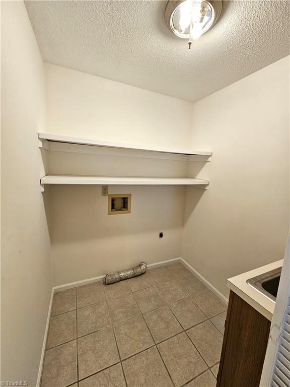 laundry room with light tile patterned floors, hookup for a washing machine, hookup for an electric dryer, and a textured ceiling