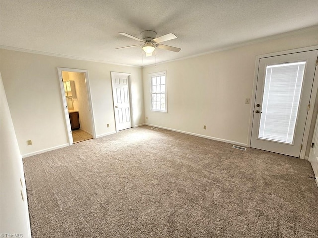 carpeted spare room featuring crown molding, ceiling fan, and a textured ceiling