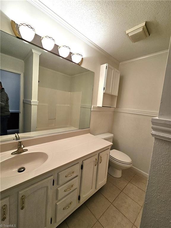 bathroom featuring tile patterned flooring, vanity, crown molding, and a textured ceiling