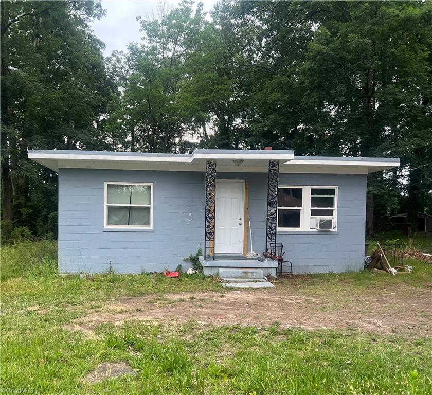 bungalow-style house with concrete block siding and cooling unit