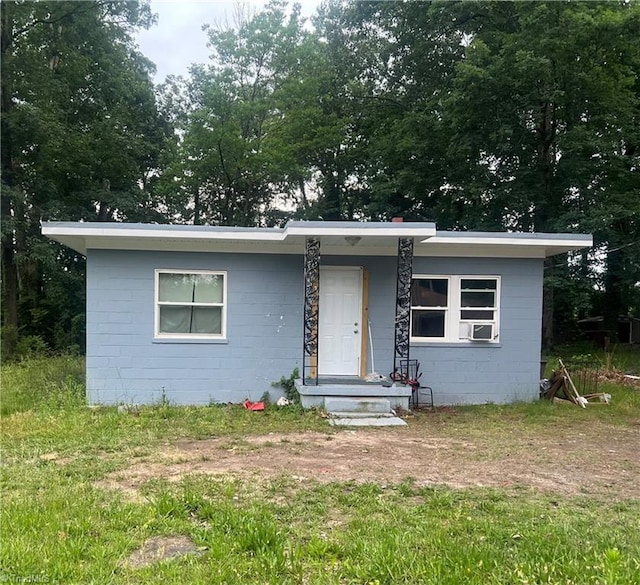 bungalow-style house with concrete block siding and cooling unit