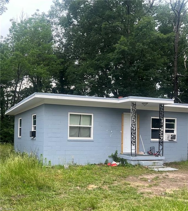 view of front of home featuring cooling unit, concrete block siding, and a porch