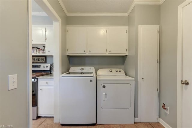 washroom with light tile patterned floors, washing machine and dryer, cabinet space, and crown molding