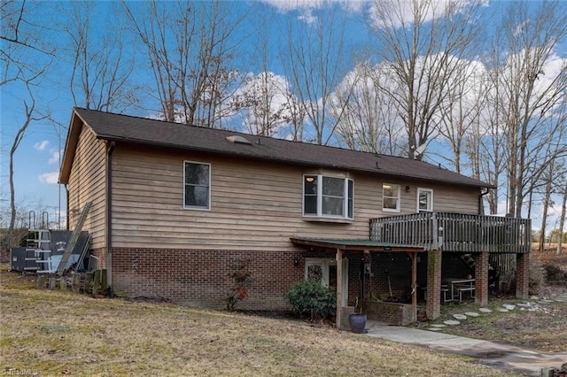 rear view of property featuring a yard, a wooden deck, and brick siding