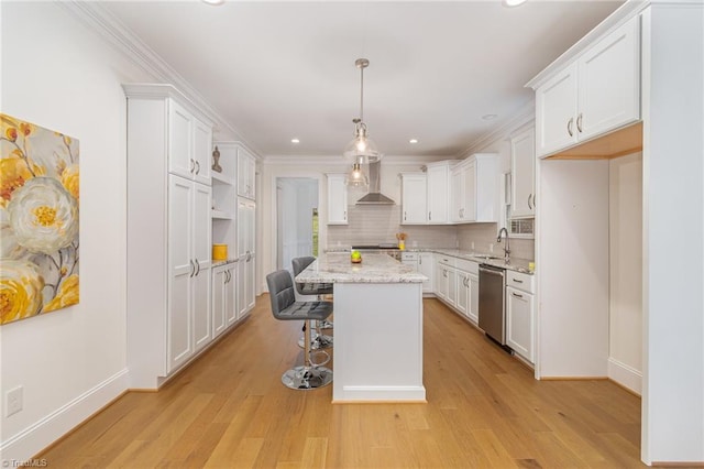 kitchen with a center island, white cabinetry, stainless steel dishwasher, and wall chimney range hood