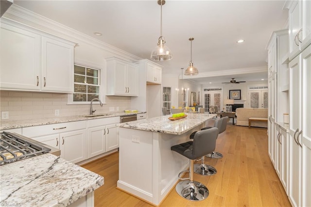 kitchen featuring ceiling fan, sink, a kitchen island, white cabinets, and light wood-type flooring