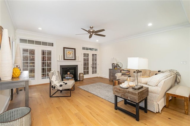 living room with crown molding, french doors, ceiling fan, and light wood-type flooring