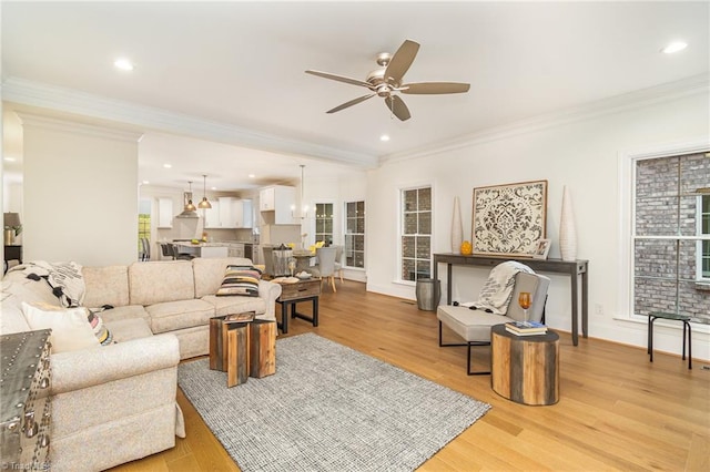 living room featuring a wealth of natural light, light wood-type flooring, ceiling fan, and ornamental molding