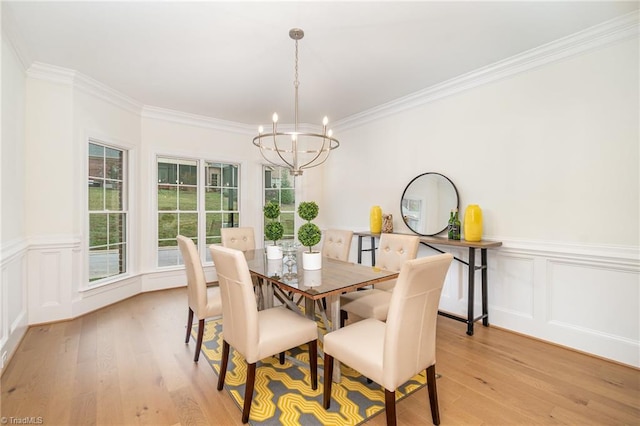 dining area with an inviting chandelier, light hardwood / wood-style floors, and ornamental molding