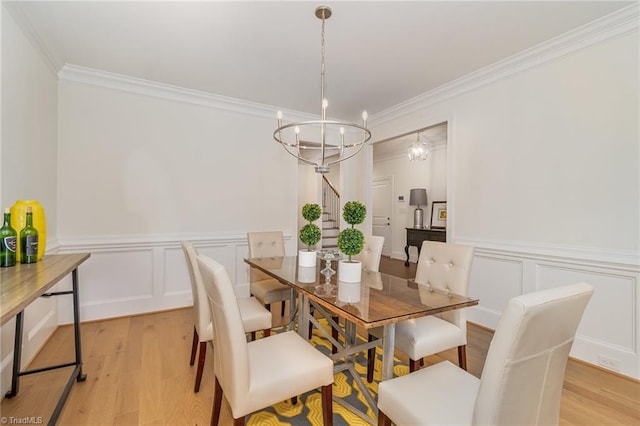 dining area with crown molding, a chandelier, and light wood-type flooring