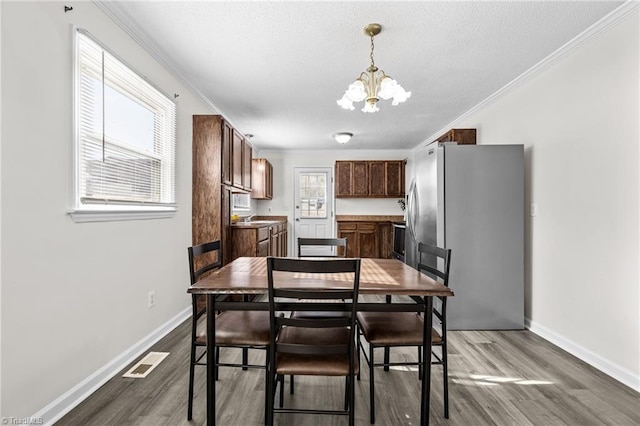 kitchen featuring hardwood / wood-style flooring, an inviting chandelier, crown molding, and stainless steel fridge