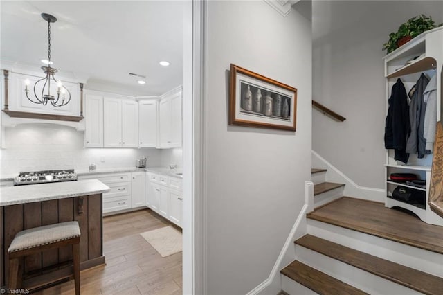 1623 Angus Ridge Dr, Kernersville, NC 27284 - kitchen featuring white cabinetry, light wood-style floors, backsplash, a chandelier, and stove