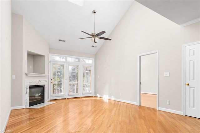 unfurnished living room featuring ceiling fan, hardwood / wood-style flooring, a high end fireplace, and high vaulted ceiling