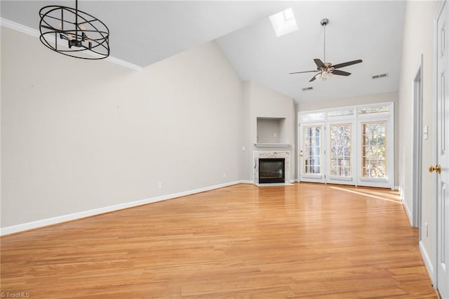 unfurnished living room with light wood-type flooring, high vaulted ceiling, a premium fireplace, a skylight, and ceiling fan