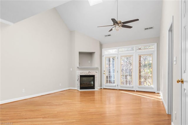 unfurnished living room with ceiling fan, light hardwood / wood-style floors, a high end fireplace, and high vaulted ceiling