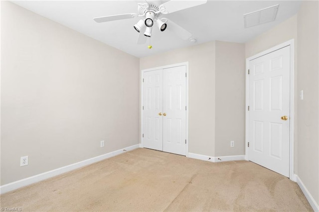 unfurnished bedroom featuring a closet, light colored carpet, and ceiling fan