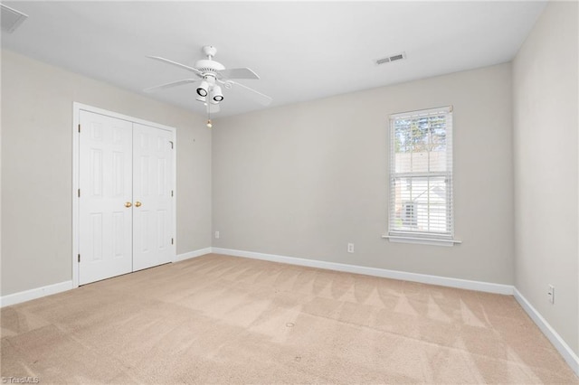 unfurnished bedroom featuring light carpet, ceiling fan, and a closet