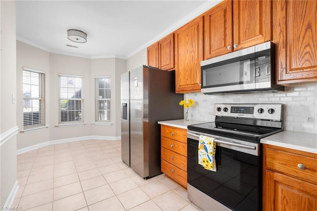 kitchen with light tile patterned flooring, decorative backsplash, ornamental molding, and stainless steel appliances