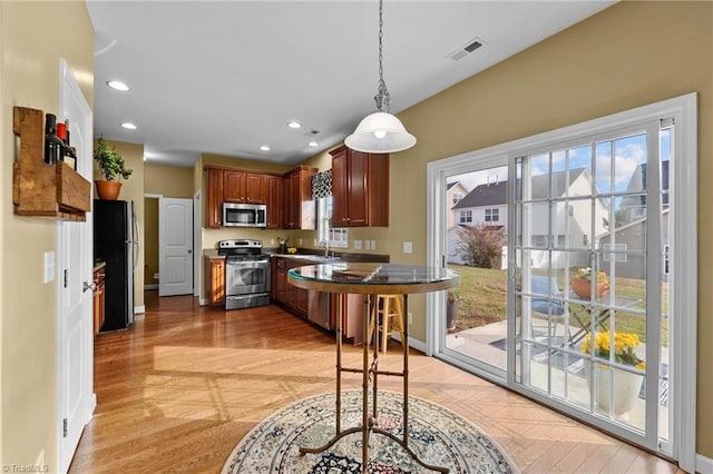 kitchen with sink, stainless steel appliances, decorative light fixtures, and light hardwood / wood-style floors