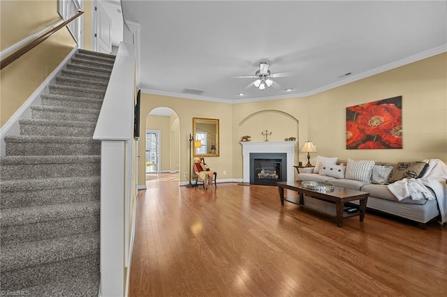 living room featuring hardwood / wood-style floors, ceiling fan, and ornamental molding