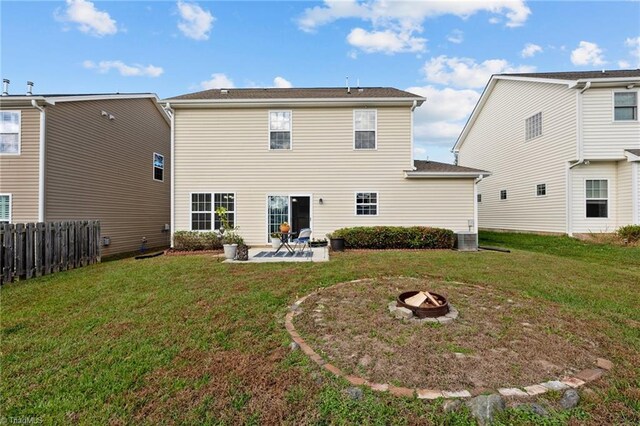 rear view of property featuring a yard, an outdoor fire pit, and a patio area