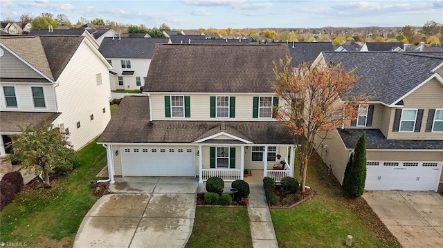 view of front of property featuring a garage, covered porch, and a front yard