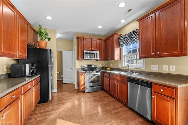 kitchen with sink, appliances with stainless steel finishes, and light hardwood / wood-style flooring