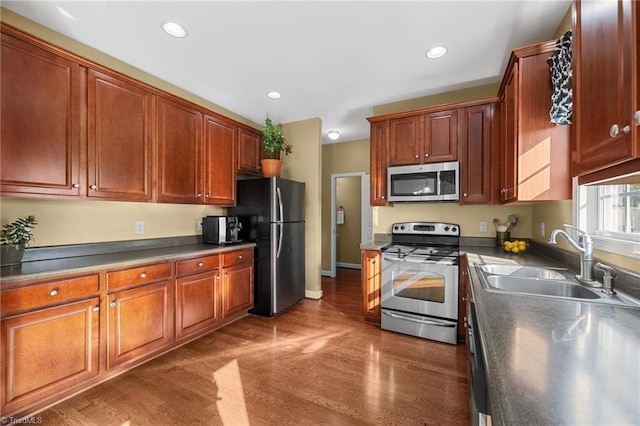 kitchen featuring appliances with stainless steel finishes, dark wood-type flooring, and sink