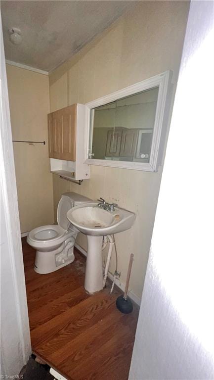 bathroom with hardwood / wood-style floors, toilet, and crown molding