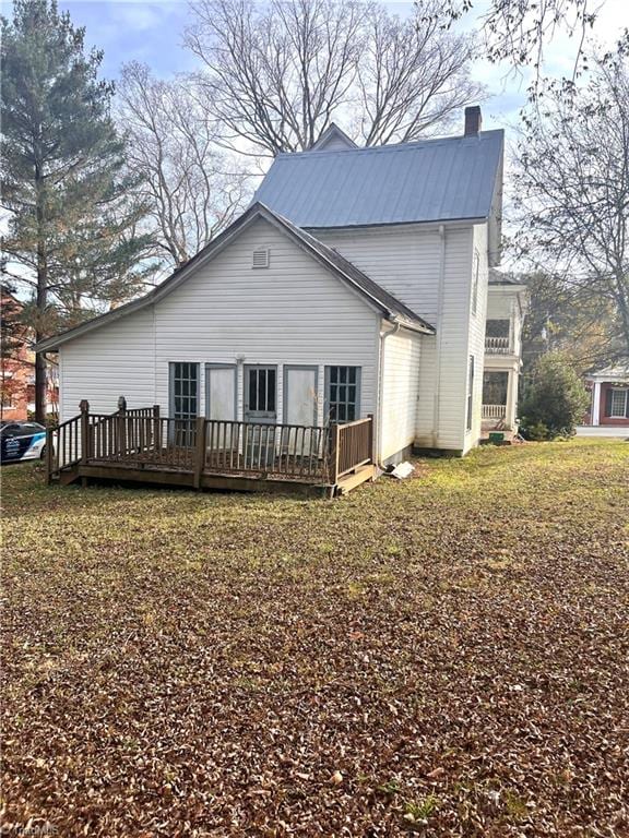 back of property featuring a deck and a lawn