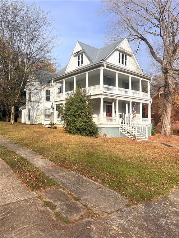 view of front of property with a porch, a front yard, and a balcony