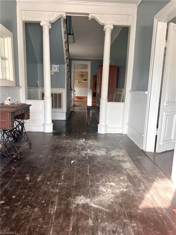 unfurnished dining area featuring dark wood-type flooring and ornate columns