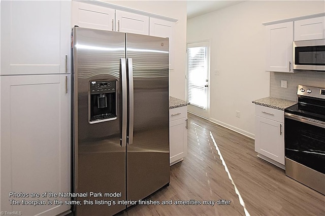 kitchen with light stone counters, stainless steel appliances, and white cabinetry
