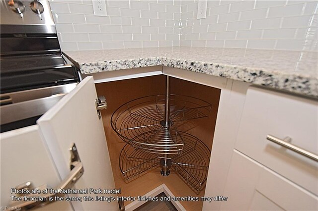 room details featuring stainless steel electric stove, decorative backsplash, and light stone counters