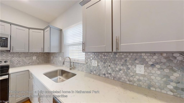 kitchen with decorative backsplash, light countertops, gray cabinets, a sink, and stainless steel electric range oven