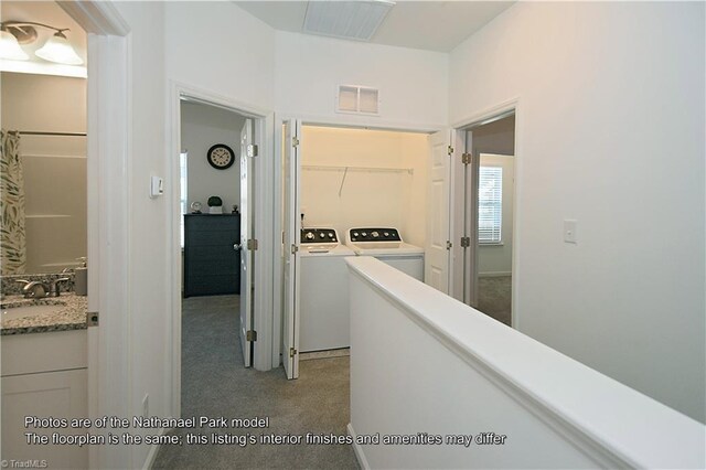 hallway with a sink, carpet floors, washing machine and dryer, and visible vents
