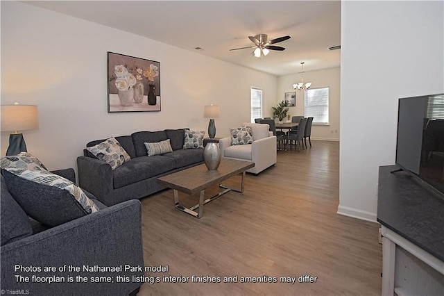 living area with baseboards, visible vents, wood finished floors, and ceiling fan with notable chandelier