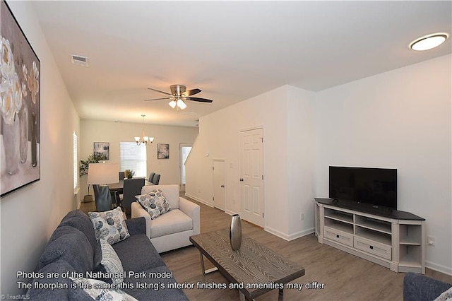 living area featuring baseboards, ceiling fan with notable chandelier, wood finished floors, and visible vents