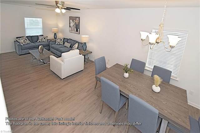 dining space with baseboards, ceiling fan with notable chandelier, and light wood-type flooring