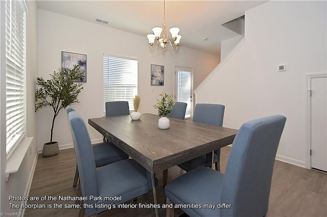 dining area with a chandelier, baseboards, visible vents, and wood finished floors