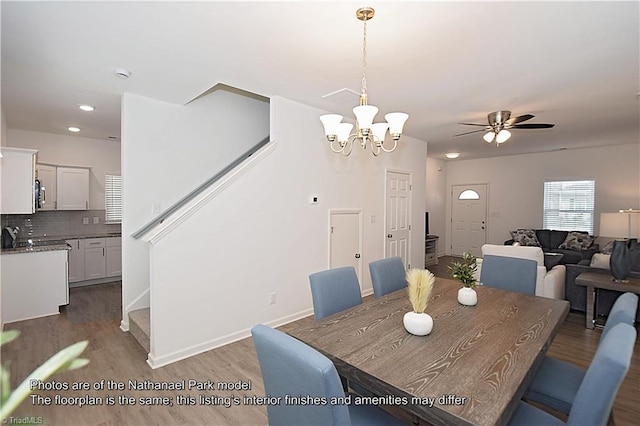 dining area featuring recessed lighting, stairs, ceiling fan with notable chandelier, and wood finished floors