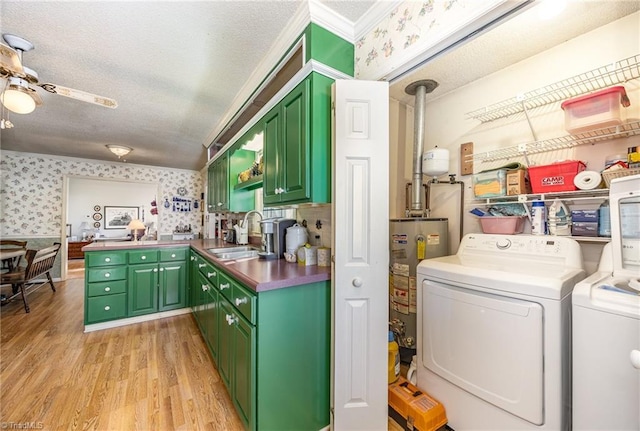 laundry area featuring sink, a textured ceiling, light wood-type flooring, washing machine and dryer, and water heater