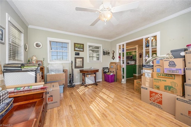 interior space with ceiling fan, ornamental molding, a textured ceiling, and light wood-type flooring