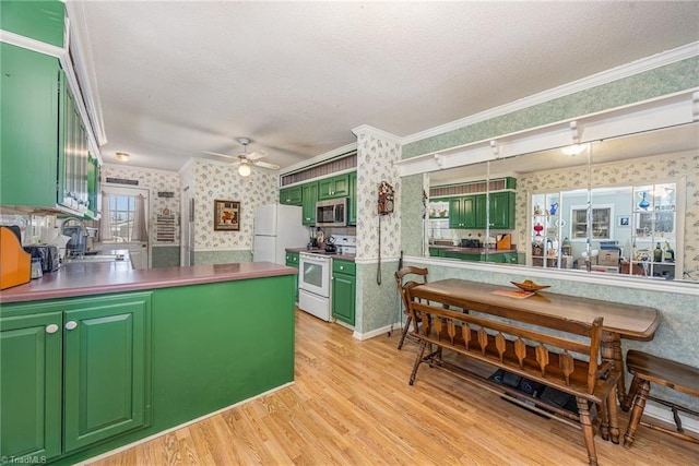 kitchen featuring sink, white appliances, green cabinets, kitchen peninsula, and light wood-type flooring