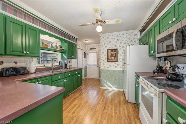 kitchen with sink, light wood-type flooring, ornamental molding, green cabinets, and white appliances