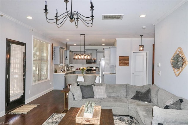 living room with a notable chandelier, dark hardwood / wood-style flooring, and ornamental molding