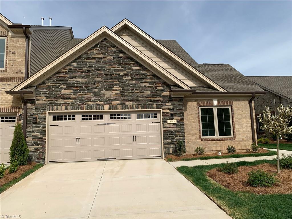 craftsman-style home featuring driveway, a garage, stone siding, and roof with shingles