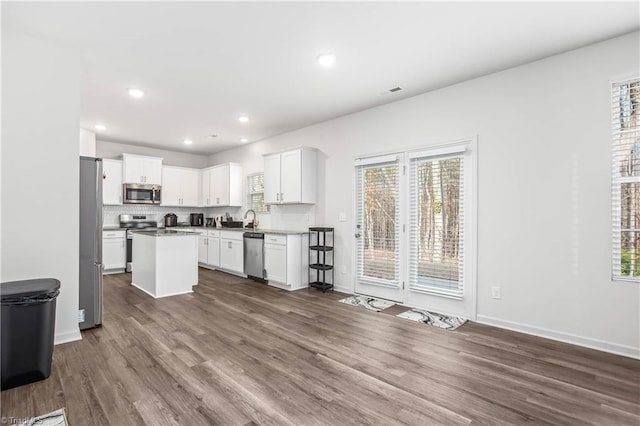 kitchen with stainless steel appliances, a center island, dark wood-type flooring, and white cabinets